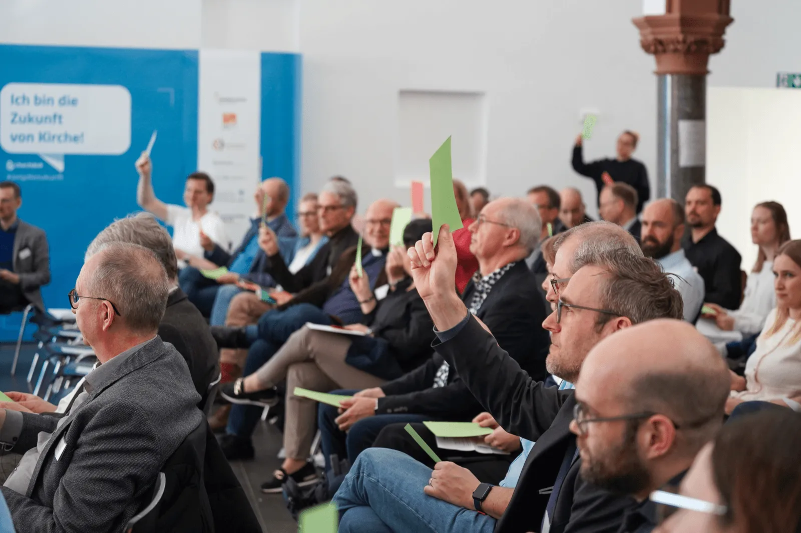 Teilnehmende beim ChurchDesk Summit heben grüne Karten